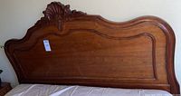 Full view of wooden headboard with carved shell detail and smooth wood panel