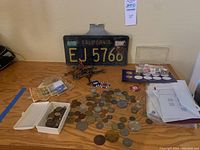 Full view of lot contents including old California license plate EJ 5766, coins, poker chip magnets, keys, and unopened envelopes of stamps