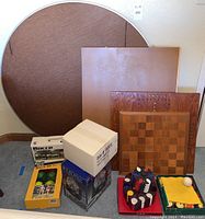 Contains poker table top leaning against wall, vintage pool ball set, two boxed bocce sets, Po-Ke-No game, puzzle board and wooden boards visible