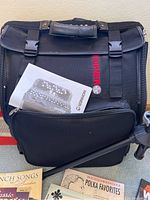 Hohner backpack-style case front with red HOHNER logo, sheet music and music stand partially visible