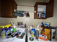 Photo displaying an array of household cleaning supplies including OxiClean bottles, Combat ant bait, furniture sliders, shelf liner, and other cleaning accessories.