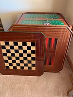 Game boards leaning against wall: chess/checkers board, backgammon board, green felt card table top