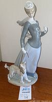 Front view of Lladro Lady with Shawl figurine holding dog on leash, standing on oval base.