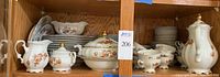 Shelved china set with visible cream, sugar, gravy boat, covered bowl, tea cups, plates, and platters.