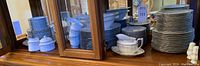 Overall view of stacked plates, bowls, cups and saucers in a cabinet