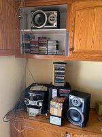 Photo of stereo system with RCA CD changer and Panasonic speakers on a wooden counter with two CD stands containing stacks of CDs.