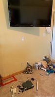 Sony flat screen TV mounted on wall with cables visible on floor below and adjacent clutter.