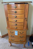 Full view of the wooden jewelry chest showing drawers, side compartments, brass handles and chest design.
