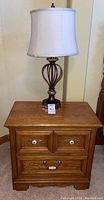 Nightstand with lamp on top showing overall condition and style.