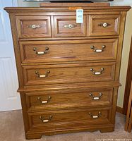 Front view showing five drawers with ceramic and brass pulls. Top row has three smaller drawers, below are four larger drawers.
