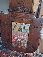 Front view of oak framed mirror with carved crest and four brass coat hooks.