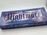 Top view of vintage Nightmare video board game box showing gothic styled logo and decorative borders in blue, purple, and pink hues.