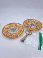 Two ornate round bone china plates and metal stand rod disassembled for display