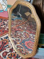 Full view of the vintage gilt-framed wall mirror showing its overall shape and condition.