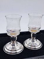 Pair of Birks sterling silver candlestands with glass hurricane shades set in a black velvet display.
