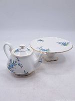 Teapot and footed snacks plate side by side on white background