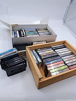 Photo of a wooden case filled with cassette tapes by various artists, some labeled.
