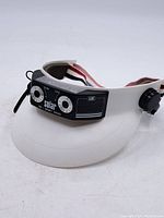 White visor with black solar AM sport radio unit mounted on the front showing volume and tuning dials and AIM branding.