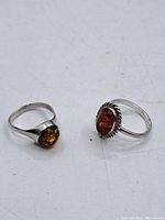 Photo showing two vintage sterling silver rings with natural amber stones on a white background.