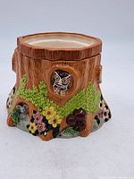 Front view of the vintage tree trunk cookie jar with owl and floral decorations.