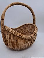 Side angle of the brown wicker basket showing handle and body shape