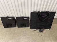 Three Optex light boxes: two smaller square ones with fabric covers and one larger rectangular one in a soft carry bag, all with power adapters on the floor.