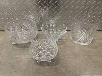 Four crystal bowls on a surface with diamond plate metal background showing a variety of cut patterns.