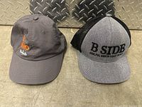 Two adjustable baseball caps side by side on diamond plate metal background.