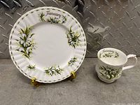 Plate and cup set showing matching January snowdrops design with flowers and gold lettering