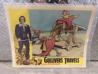 Front view of 1957 Gulliver's Travels movie lobby card with main artwork visible showing Gulliver and tiny characters and Technicolor branding.
