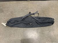 Full view of the YETI carry bag in black charcoal with YETI logo patch and shoulder strap.