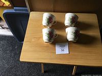 Photo of 4 antique teacups arranged on a wooden table showing the floral exterior design.