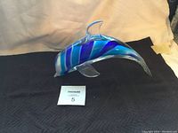 Full side view of large crystal dolphin figurine showing blue and white striped glass body with clear fins and tail.