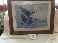 Full view of framed artwork showing three flying geese with cloudy sky background, wood frame, and matting.