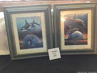 Pair of framed whale art prints signed A Metz, both showing underwater ocean scenes with orcas and dolphins.