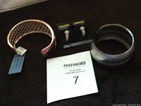 Photo of two bracelets and one pair of earrings on a dark surface, showing detailed texture of the bracelets and earrings attached to a card.