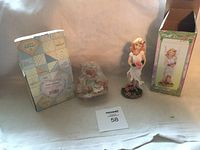 Calico Kittens figurine in box with flower girl statue and its box beside it on a white cloth backdrop.
