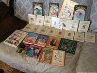 Photo showing 33 children's books spread out on couch, including vintage and storybooks.