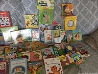Photo showing a wide selection of 28 children's books spread out on a surface with many colorful covers and familiar characters.