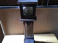 Full frontal photo of the mini grandfather clock showing the clock face and wood details