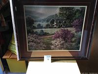 Full view of framed Raos artwork showing countryside landscape with house, trees, and lake