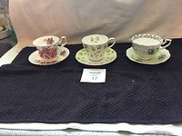 Three Royal Albert teacups and saucers arranged side by side showing different floral designs