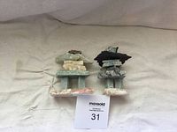 Two stacked stone luck statues side by side on a beige cloth background