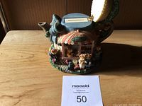 Front angle of the colorful ceramic tea pot merry go round bank on wooden table.