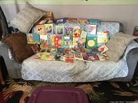 View of 43 vintage kids books arranged on a couch showing colorful covers and mixed titles.