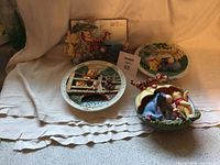 Four Winnie the Pooh themed collector plates displayed together showing distinct Pooh character scenes and 3D figurines on plates. Tigger figurine damage visible with pieces detached in front.