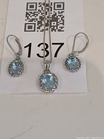 Photo of necklace and two matching earrings featuring aquamarine stones surrounded by clear crystals on silver settings.