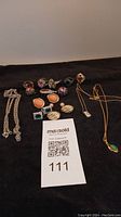 Photo shows assortment of rings, earrings, and necklaces laid out on black background with MaxSold lot card.