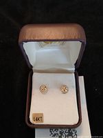 Close-up of one earring set in box showing round cut openwork design.