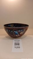 Side view of the pottery bowl showing dark burgundy and blue glaze with textured surface